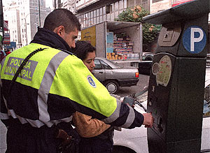 Un policía ayuda a una mujer a sacar el ticket en un parquímetro. (Villanueva)