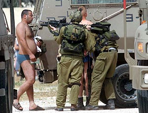 Un soldado israel apunta a uno de los presos palestinos, que permanece desnudo. (Foto: EFE)