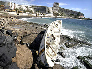 Un cayuco entre las rocas de una playa de la localidad de Los Cristianos, en Arona, Tenerife. (Foto: EFE)