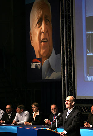 Ehud Olmert se dirige a sus seguidores ante una imagen de Ariel Sharon. (Foto: AFP)