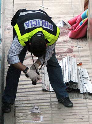 La Polica cientfica examina pruebas en la puerta de la vivienda de Alzira donde se produjo el tiroteo. (Foto: EFE)
