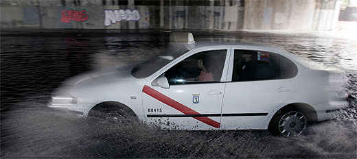 Un taxi atraviesa una 'balsa de agua' formada tras las lluvias de hoy. (Foto: J. Martinez)