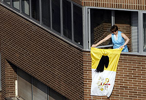 Una mujer coloca una bandera del Vaticano con un crespón negro. (Foto, AP)