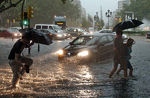 Unos ciudadanos intentan atravesar un paso de peatones durante la tromba de agua que ha cado sobre Zaragoza. (Foto: EFE)