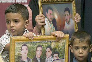 Unos nios palestinos muestran la foto de varios familiares apresados por israeles. (Foto: EFE)