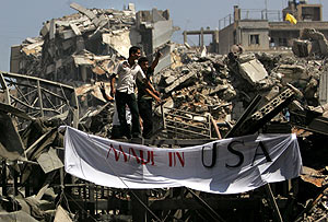 Dos libaneses colocan una pancarta en la que se lee 'Hecho por USA' en su casa derruida en Beirut. (Foto: AP)