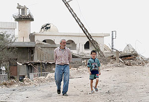 Un hombre y un nio caminan junto a una mezquita destruida en la ciudad libanesa de Maroun er Bas. (Foto: EFE)