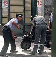Unos policas municipales retiran una moto aparcada en la acera. (Foto: C. Tejada)