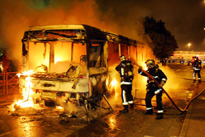 Los bomberos tratan de apagar uno de los autobuses incendiados. (Foto: AFP)