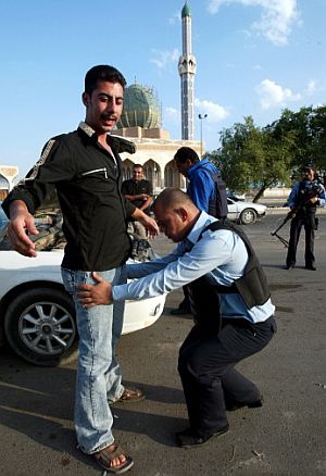 Un policía cachea a un peatón en un control en Bagdad. (Foto: AFP)