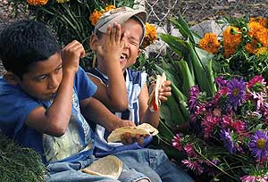 Dos nios se ren comiendo tortillas en un puesto de venta de flores de Tegucigalpa, Honduras. (Foto: EFE)