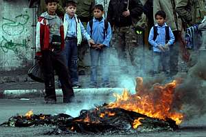 Varios escolares palestinos presencian la quema de neumticos en protesta por el asesinato de tres nios el lunes. (Foto: EFE)