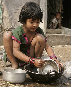 Una nia lava los cacharros de la cocina junto a su casa de Calcuta. (Foto: REUTERS)