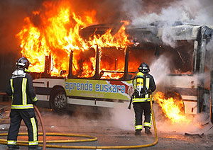 Los bomberos apagan el autobús incendiado. (Foto: EFE)