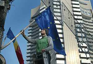Un trabajador coloca una bandera de la UE junto a la rumana en un edificio de Bucarest. (Foto: AFP)