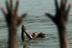 Un hindú se baña en el Ganges mientras otro fiel lanza plegarias ante el río sagrado. (Foto: AP)