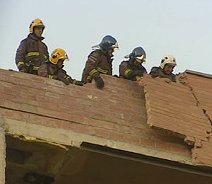 Los bomberos arrancando los trozos de fachada sueltos. (Foto: TVE)