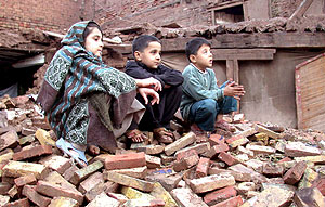 Nios de una familia desplazada sentaos en los escombros de su casa en Pakistn. (Foto: EFE)