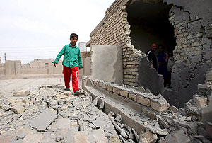 Un nio pasa junto a el muro destrozado de una casa en Bagdad. (Foto: EFE)