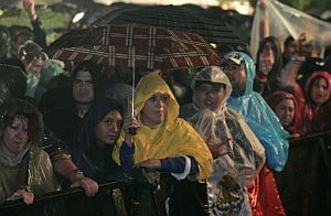 Las asistentes han tenido que sacar paraguas y chubasqueros. (Foto: EFE)