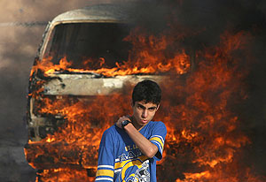 Un joven se aleja del coche en llamas a consecuencia del ataque. (Foto: AFP)