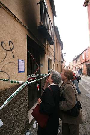 Dos mujeres leen la esquela en la fachada de la vivienda incendiada. (Foto: EFE)