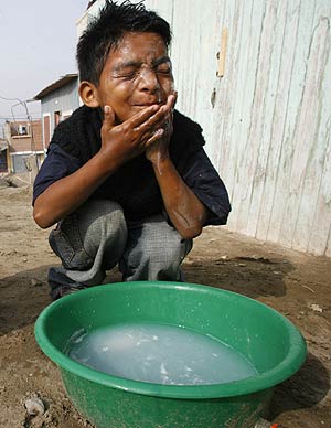 Un nio se lava la cara en un barrio de Lima, Per. (Foto: REUTERS)