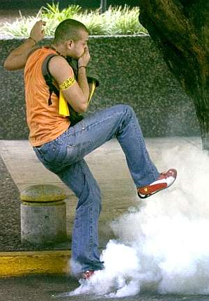 Un estudiante patea una bomba de gas lacrimgeno durante disturbios contra la polica durante una protesta en Caracas. (Foto: EFE)
