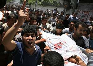 Un grupo de palestinos con el cadáver de un fallecido en los combates de los últimos días. (Foto: AFP)