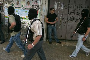 Un joven palestino observa a tres hombres armados en una calle de Ramala. (Foto: AFP)
