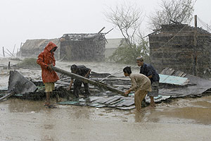 Una familia busca entre los escombros de su casa bajo una lluvia torrencial en Pakistn. (REUTERS)
