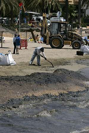 Operarios del servicio de limpieza retiran fuel en la playa de Figueretes. (Foto: EFE)