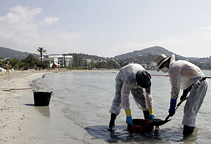 Dos operarios de limpieza, este mircoles, en la playa de Talamanca. (Foto: EFE)