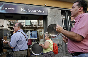 Varias personas golpean sus cacerolas frente a una oficina de Fecsa-Endesa. (Foto: EFE)