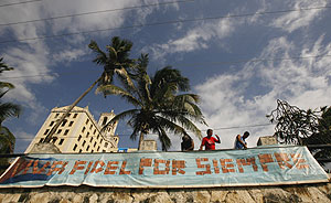 Varios trabajadores colocan un cartel sobre Fidel. (Foto: AP)