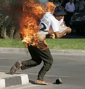 El hombre trata de quitarse la camiseta tras prenderse fuego. (Foto: EFE)