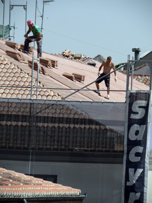 Dos obreros, sin medidas de seguridad, en el tejado del edificio. (Foto: EL MUNDO)