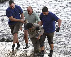 Tres personas sacan a un inmigrante del agua. (Foto: REUTERS)