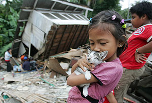 Una niña juega con un gato junto a una casa destruida en Bengkulu. (Foto: AP)