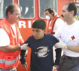 Dos miembros de Cruz Roja dan asistencia a un menor marroqu en Motril. (Foto: Paco Ayala)