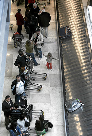 Decenas de pasajeros esperan para recoger su equipaje , ayer, en la T-4 de Barajas. (Foto: Jaime Villanueva)