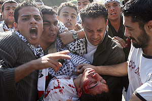 Palestinos llevan a un herido durante el homenaje a Arafat en Gaza. (Foto: AFP)