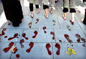 Unas mujeres dejan las huellas de sus pies teidos de rojo en Sevilla. (Foto: EFE)