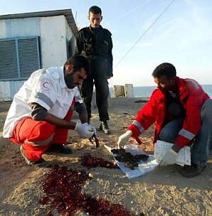 Miembros de la Media Luna Roja recogen restos humanos tras un ataque israel. (AFP)