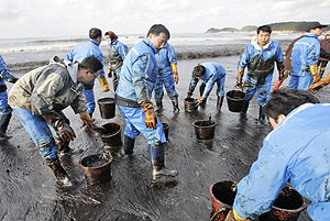 Un grupo de voluntarios limpiando una de las playas afectadas. (Foto: AP)