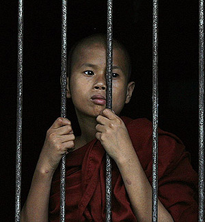 Un joven monje observa los actos de protesta desde una verja. (Foto: Reuters)