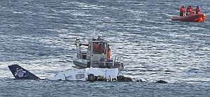 Una embarcacin de la Guardia Costera se dispone a remolcar los restos de la avioneta que siguen a flote. (Foto: AP)