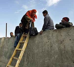 Varios palestinos superan el muro de Rafah con la ayuda de una escalera. (Foto: AFP)