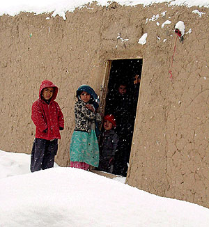 Nios afganos miran la nieve en la puerta de su casa en Herat. (EFE)