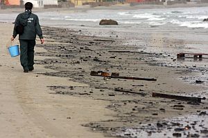 Un agente recoge resduos de hidrocarburo en la playa de la Concha, en Algeciras. (Foto: EFE)